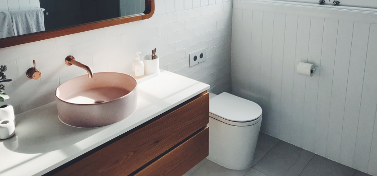 white bathroom with pink basin and copper tapware